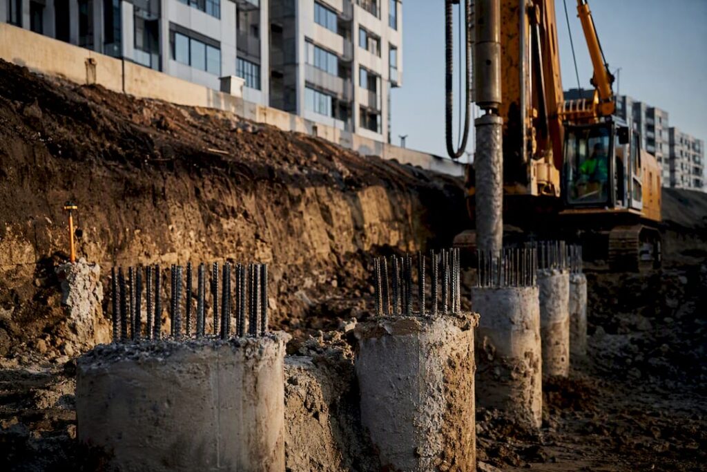 Piling rig beside exposed foundation piles